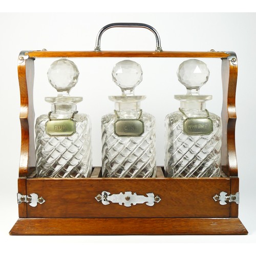 153 - An early 20th Century three decanter oak tantalus, with silver plated fittings, the three spirit dec... 