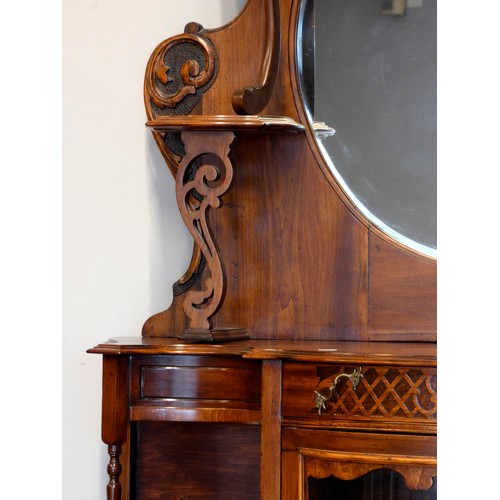 378 - A Victorian mahogany ornate display cabinet, the shaped raised back set with a bevelled oval mirror ... 