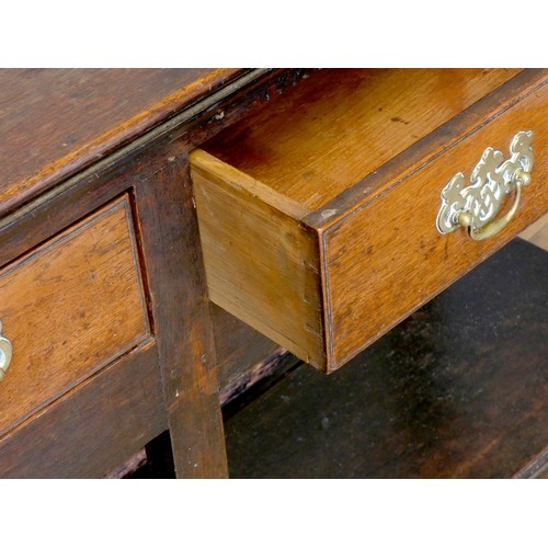 396 - A Georgian oak dresser base, the projecting top fitted with two long drawers having brass loop handl... 