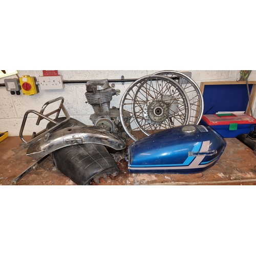 89 - A collection of Honda 125 spares, including partial engine, tank, seat, front and rear wheels.