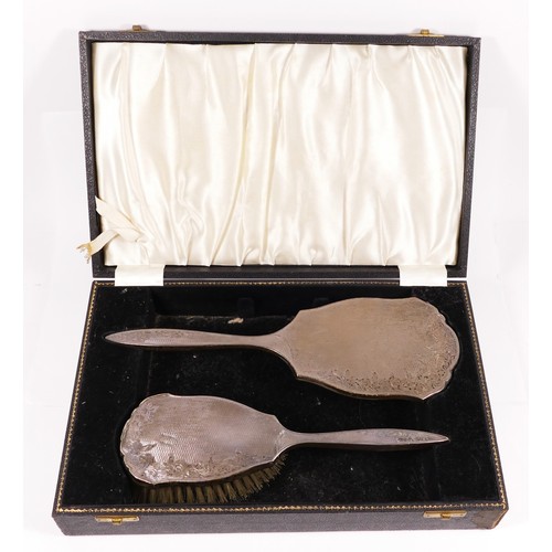 105 - A silver hand mirror and brush set, Birmingham 1957, engine turned decoration, case.