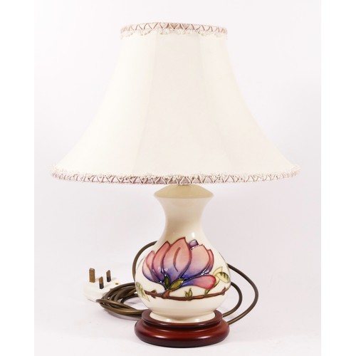 76 - A Moorcroft magnolia pattern table lamp, decorated against an ivory ground, with cream shade.