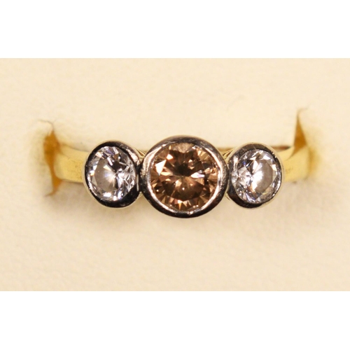 69 - An 18ct gold three stone brilliant cut diamond ring, collet set with a champagne stone, estimated to... 