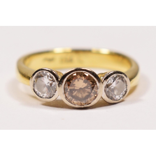 69 - An 18ct gold three stone brilliant cut diamond ring, collet set with a champagne stone, estimated to... 