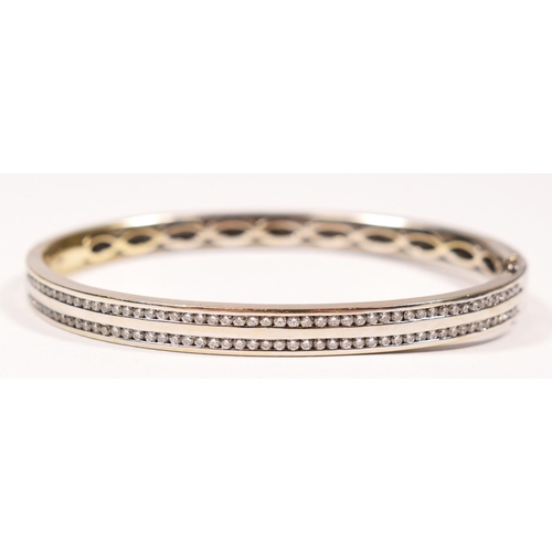 71 - An 18ct white gold and brilliant cut diamond hinged bangle, channel set with two rows of fifty stone... 