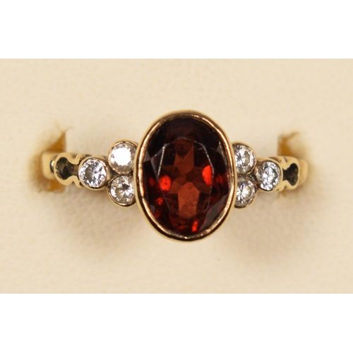 77 - A 9ct gold, garnet and brilliant cut diamond ring, collet set with an oval mixed cut stone, trefoil ... 