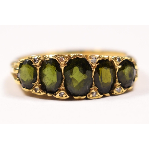 82 - An 18ct gold five stone green tourmaline ring, carved claw set with mixed cut stones, diamond points... 