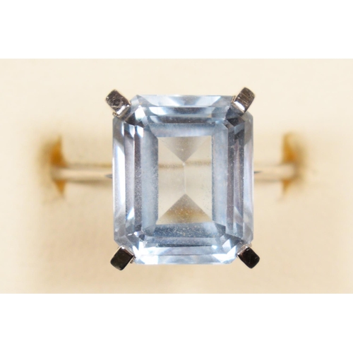 83 - A white gold and synthetic blue spinel ring, tests as 18ct gold, claw set with an emerald cut stone,... 