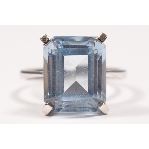 83 - A white gold and synthetic blue spinel ring, tests as 18ct gold, claw set with an emerald cut stone,... 