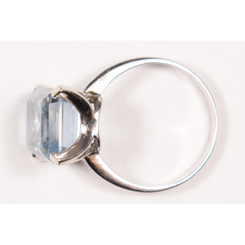 83 - A white gold and synthetic blue spinel ring, tests as 18ct gold, claw set with an emerald cut stone,... 