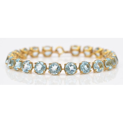 84 - A gold and blue topaz line bracelet, claw set with brilliant cut stones, tested as 9ct gold, silver ... 