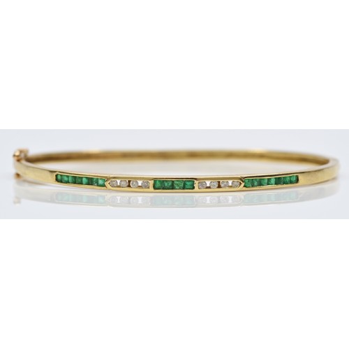 88 - A 14K gold emerald & diamond hinged bangle, channel set with brilliant cut diamonds and square cut e... 