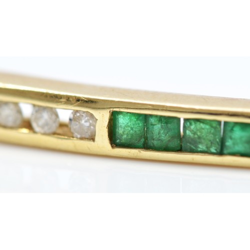 88 - A 14K gold emerald & diamond hinged bangle, channel set with brilliant cut diamonds and square cut e... 