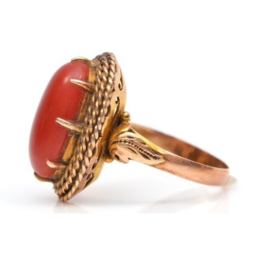 120 - A rose gold and coral dress ring, stamped 18K, the cabochon stone 17 x 9mm, O, 12gm