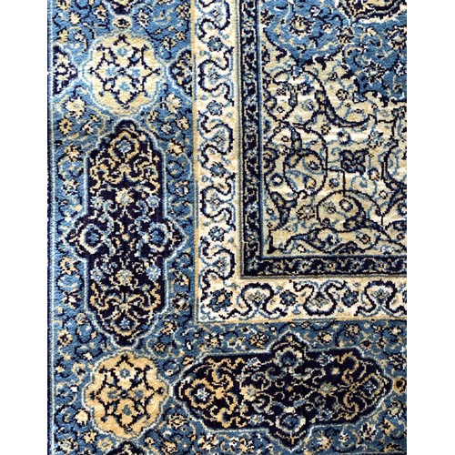 227 - A Persian Kashan style woven wool rug with a floral pattern on a blue ground with triple guard borde... 