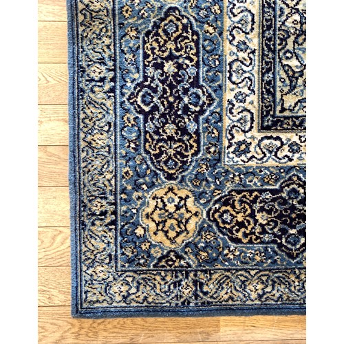 227 - A Persian Kashan style woven wool rug with a floral pattern on a blue ground with triple guard borde... 