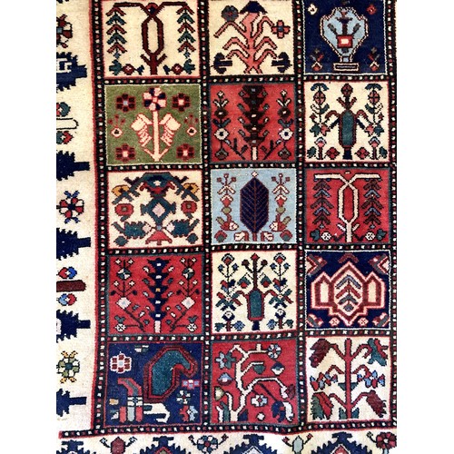 228 - A Persian Bakhtiari woven wool rug, having burgundy and ivory ground with square floral motifs and r... 