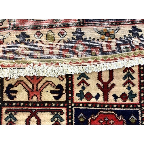 228 - A Persian Bakhtiari woven wool rug, having burgundy and ivory ground with square floral motifs and r... 