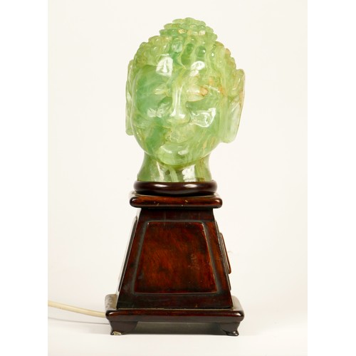 242 - A carved green hardstone Buddha head lamp, mounted on a mahogany stand, 29cm.