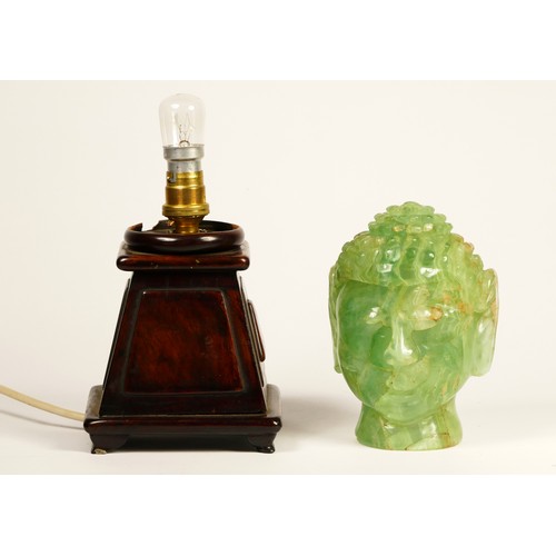 242 - A carved green hardstone Buddha head lamp, mounted on a mahogany stand, 29cm.