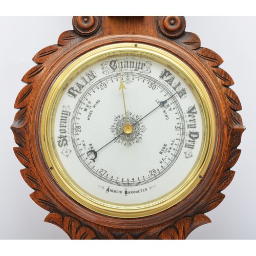 310 - A Victorian carved oak aneroid wheel barometer, with white glass dial and separate thermometer, 88cm