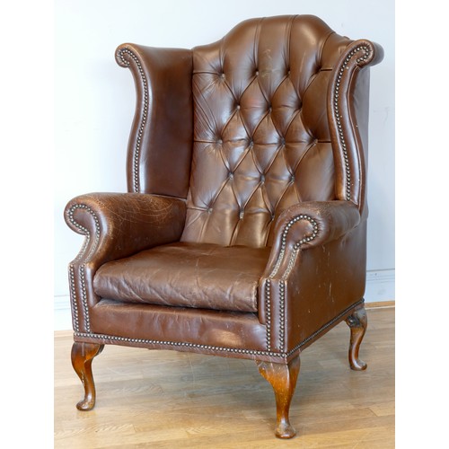 338 - A pair of Georgian style wingback armchairs, upholstered in tan leather with buttoned backs, raised ... 