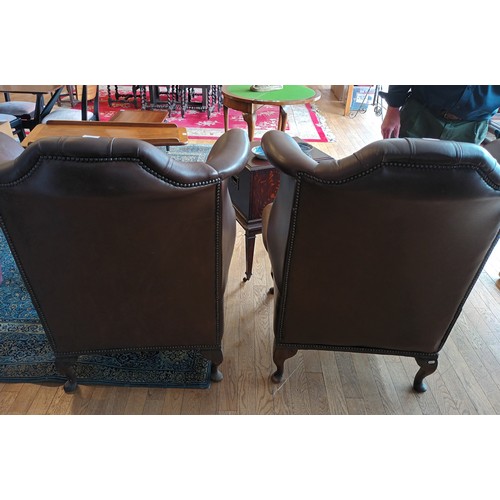 338 - A pair of Georgian style wingback armchairs, upholstered in tan leather with buttoned backs, raised ... 