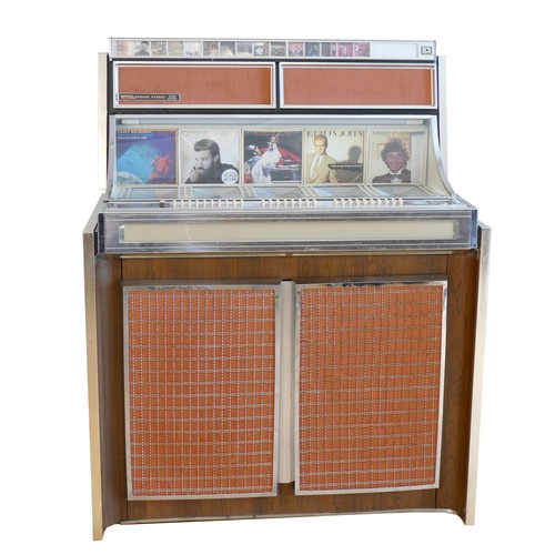A Seeburg LPC480 stereo jukebox, c.1964, 3 way audio, valve powered (serial number 160743), 160 selections, hinged front opens to reveal inner workings, side mounted cashbox, with key, hinged glassed top opens to reveal housings for vinyl singles with corresponding legend for selection combinations, steel frame with veneered wood panelling, decorated with peach coloured fabric and wire mesh speaker grills, on castors, 103 x 131 x 58cm, together with a A Seeburg Consolette wall mounted jukebox, model SCH 3-4, with stereo speakers, three volume keys and selector keys, moulded plastic case over a metal frame, with glazed front panel, plastic dial for turning the song pages, mounting holes on the rear, 39 x 35 x 17cm (2)