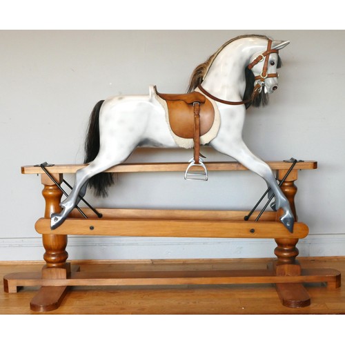 A child's rocking horse, composite body with horse hair tail and mane, leather tac and saddle, metal stirrups, on a wooden frame on turned legs, 135 x 120 x 60cm