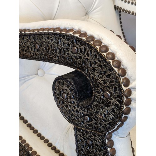 298 - A substantial cream leather rocking chair, with middle eastern inspired metal work decoration, possi... 