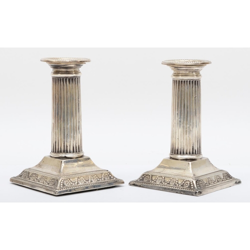 46 - A silver pair of Corinthian column desk candlesticks, by Dixons, Sheffield 1934, raised on swag embo... 