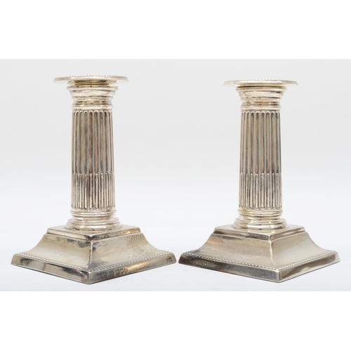 44 - A Victorian silver pair of Corinthian column desk candlesticks, London 1900 raised on beaded bases, ... 