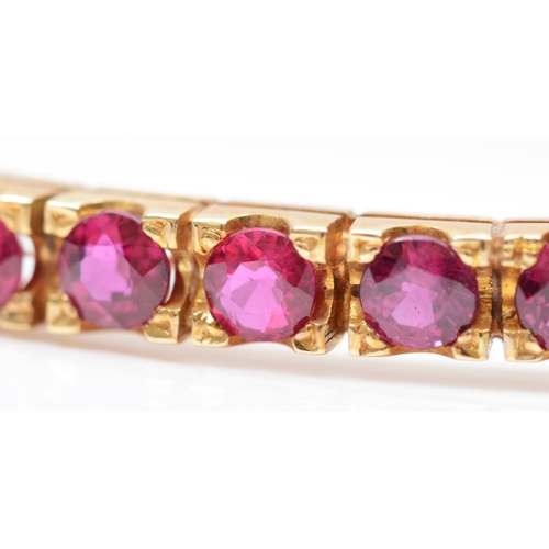 81 - A 9ct gold and ruby hinged bangle, Birmingham 1986, claw set with 17 brilliant cut stones, internal ... 