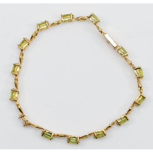 133 - A 10K gold diamond and peridot line bracelet, claw set with a navette cut stone, approximately 0.40c... 