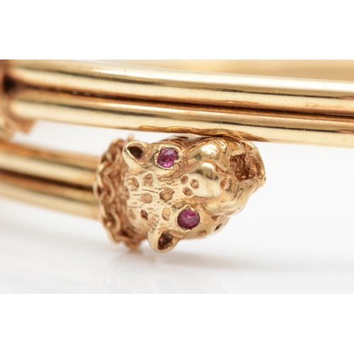 180 - A vintage 9ct gold sprung bangle, Birmingham 1989, with leopards head terminals, ruby set eyes, 9.6g... 