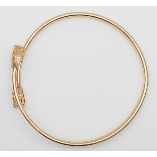 180 - A vintage 9ct gold sprung bangle, Birmingham 1989, with leopards head terminals, ruby set eyes, 9.6g... 