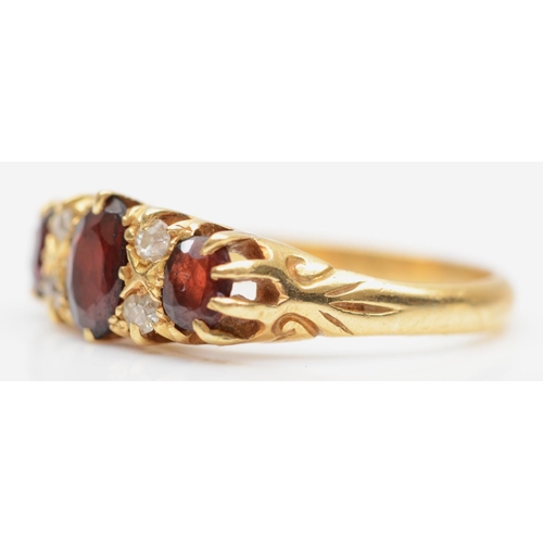 185 - An Edwardian 18ct gold garnet three stone ring, with rose diamonds between, marks erased by sizing, ... 