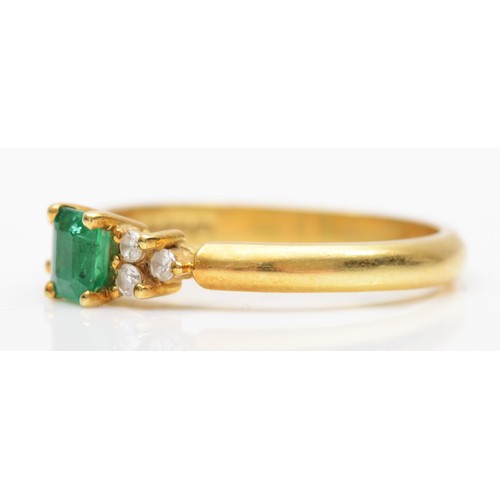 149 - An 18ct gold emerald and diamond ring, claw set with an emerald cut stone flanked by brilliant cut t... 