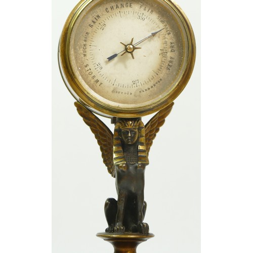 393 - A late 19th century brass aneroid barometer, raised on a bronzed patinated sphinx, to a brass stand ... 