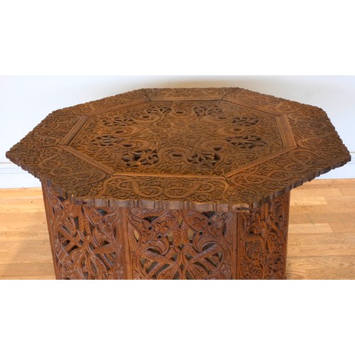 559 - An Anglo-Indian octagonal hardwood occasional table, on folding base, with intricate relief carved d... 