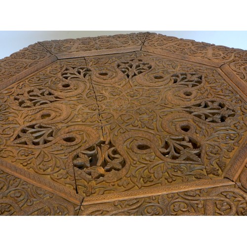 559 - An Anglo-Indian octagonal hardwood occasional table, on folding base, with intricate relief carved d... 