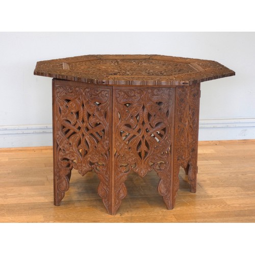 559 - An Anglo-Indian octagonal hardwood occasional table, on folding base, with intricate relief carved d... 