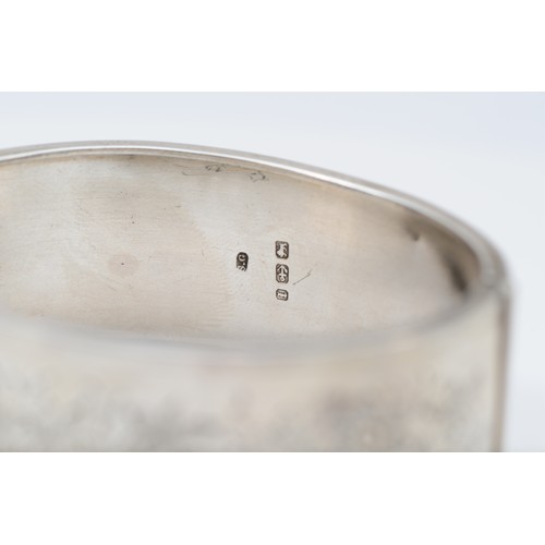 164 - A Victorian silver hinged bangle, Birmingham 1885, with floral engraved decoration 25mm wide, intern... 