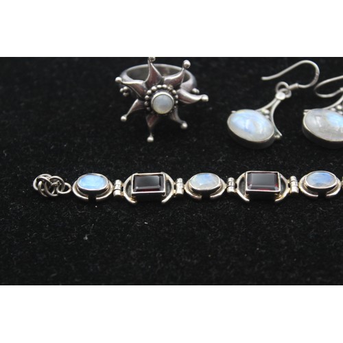 173 - A silver garnet and moonstone bracelet, a ring, cross pendant and pair of ear rings, 46gm