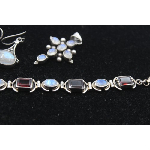 173 - A silver garnet and moonstone bracelet, a ring, cross pendant and pair of ear rings, 46gm