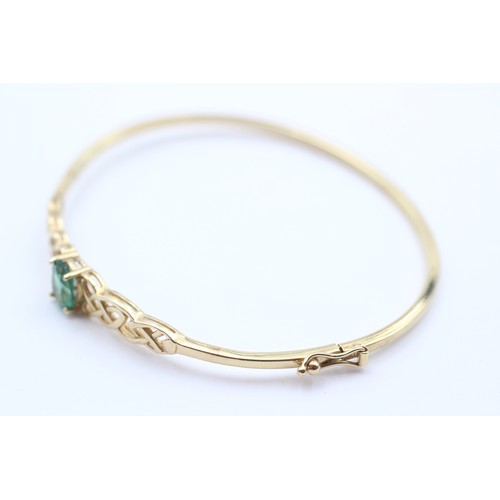 381 - A 9ct gold and green stone twist opening bangle, internal 60 x 52mm, 4.6gm