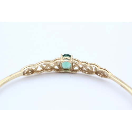 381 - A 9ct gold and green stone twist opening bangle, internal 60 x 52mm, 4.6gm