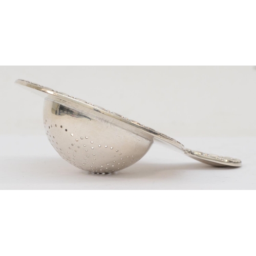 34 - A continental silver tea strainer with cast beaded rim, bearing control mark, 13 x 9cm, 67gm.