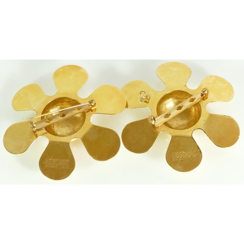 148 - Moschino, two matching flower gold plated brooches, 7.5cm.