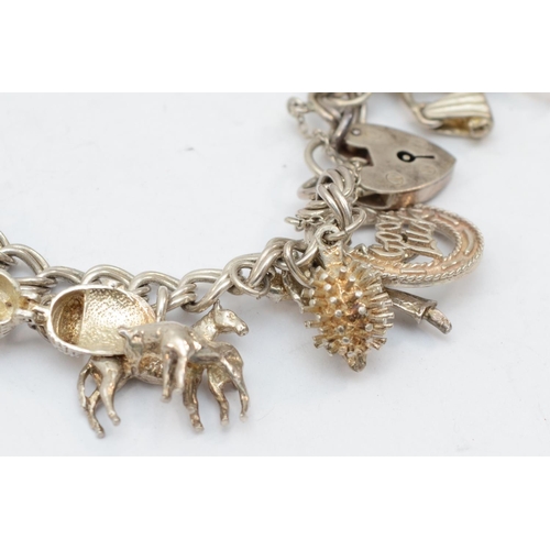 202 - A silver charm bracelet with twenty two charms, 67gm.